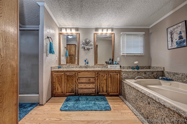 bathroom featuring a textured ceiling, hardwood / wood-style floors, separate shower and tub, ornamental molding, and vanity