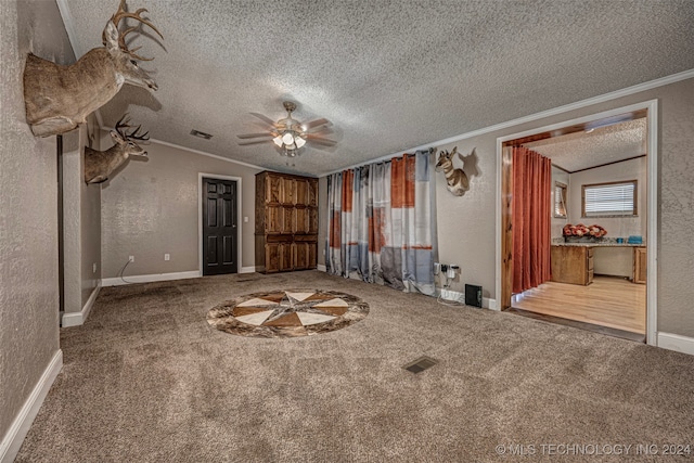 carpeted spare room featuring a textured ceiling, ornamental molding, and ceiling fan