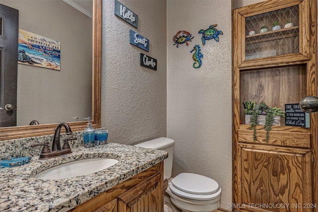 bathroom with crown molding, vanity, and toilet