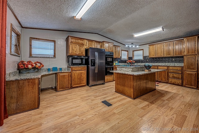 kitchen with light hardwood / wood-style flooring, black appliances, a center island, and a healthy amount of sunlight