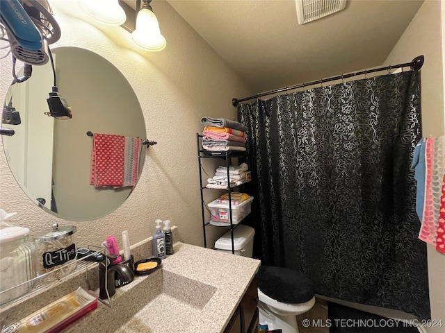 bathroom featuring curtained shower, vanity, and toilet