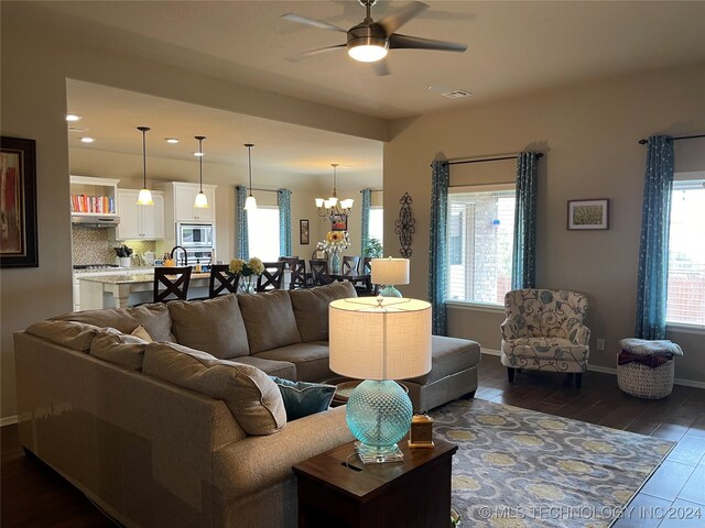 living room featuring ceiling fan with notable chandelier and dark hardwood / wood-style floors