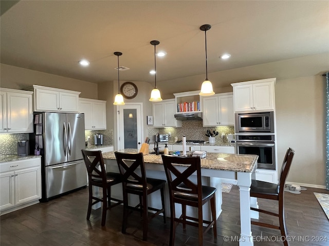 kitchen featuring hanging light fixtures, tasteful backsplash, a center island with sink, white cabinetry, and stainless steel appliances