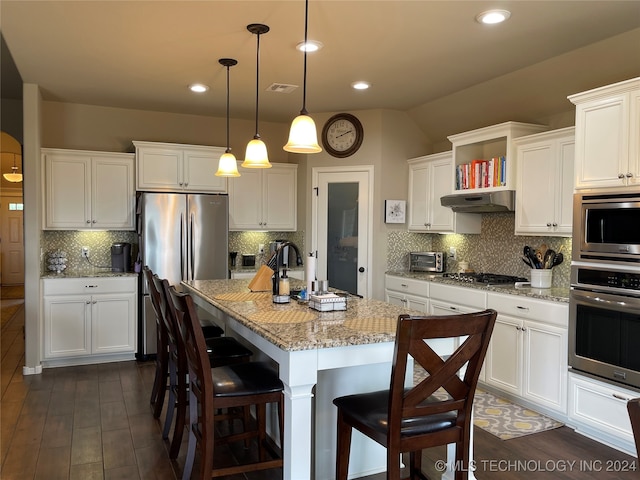 kitchen with decorative backsplash, a center island with sink, appliances with stainless steel finishes, and decorative light fixtures