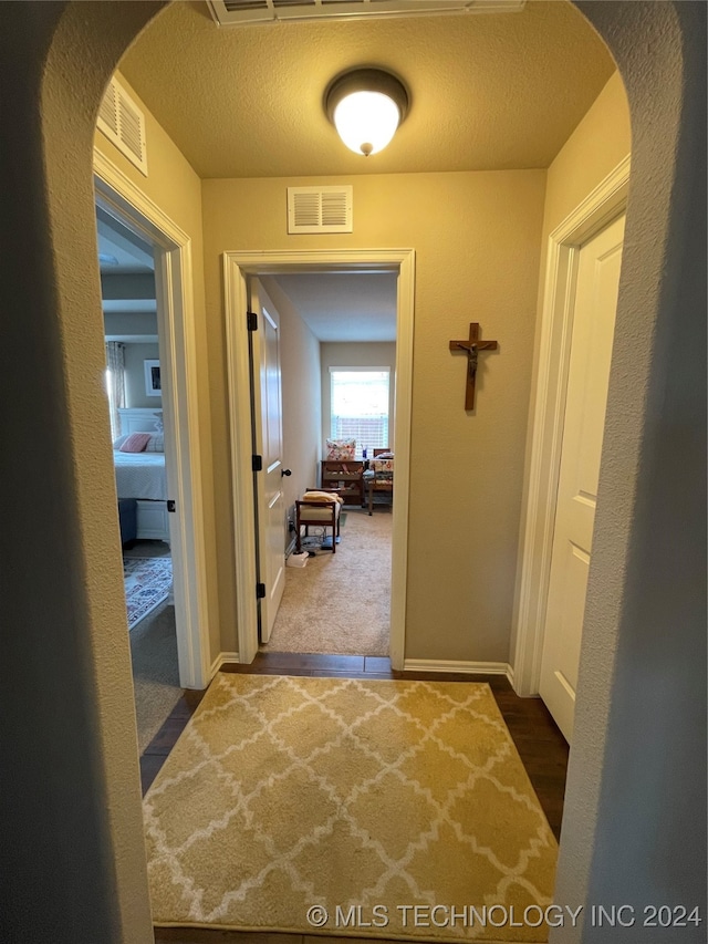 corridor featuring a textured ceiling and carpet