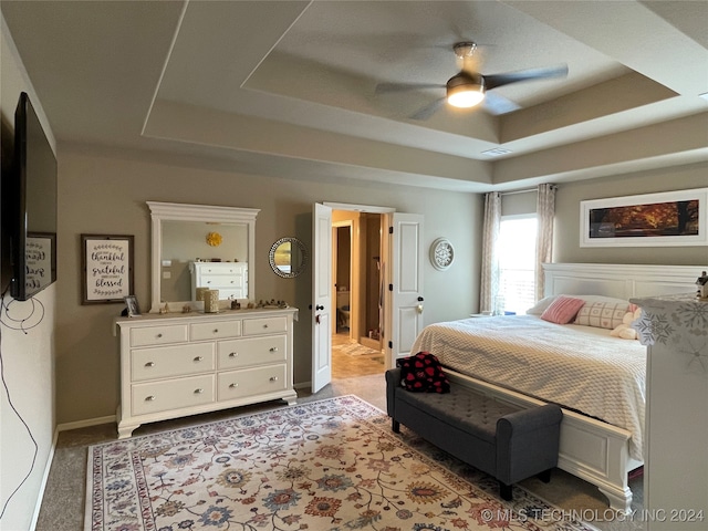 carpeted bedroom featuring a tray ceiling and ceiling fan