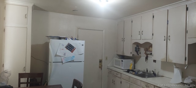 kitchen with sink, white appliances, and white cabinetry