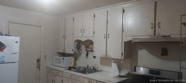 kitchen featuring sink, white appliances, and white cabinetry