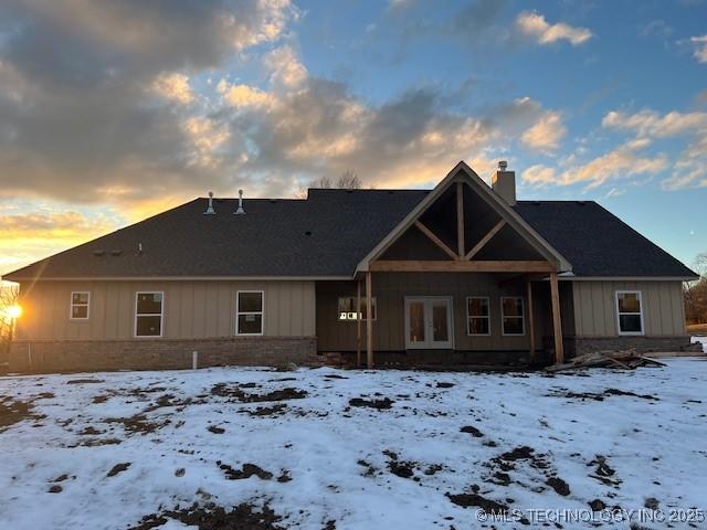 snow covered back of property with french doors