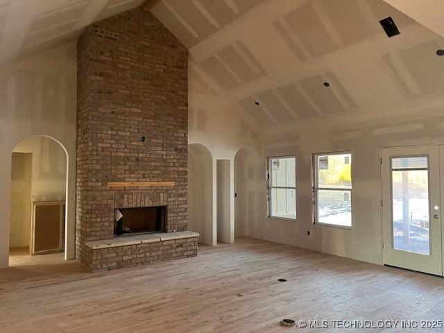 unfurnished living room with french doors, a fireplace, high vaulted ceiling, and light hardwood / wood-style flooring