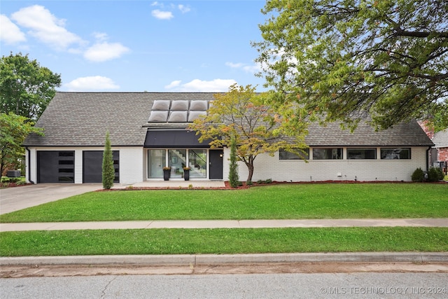 view of front of house with a garage, central air condition unit, and a front yard