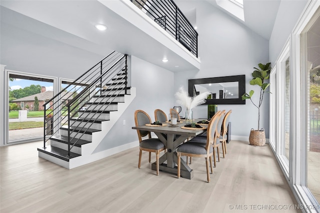 dining space with a high ceiling, light hardwood / wood-style floors, and a skylight