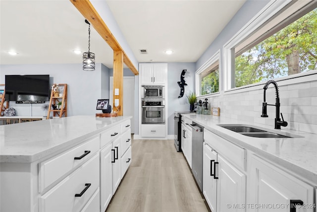 kitchen with pendant lighting, light wood-type flooring, sink, white cabinets, and appliances with stainless steel finishes