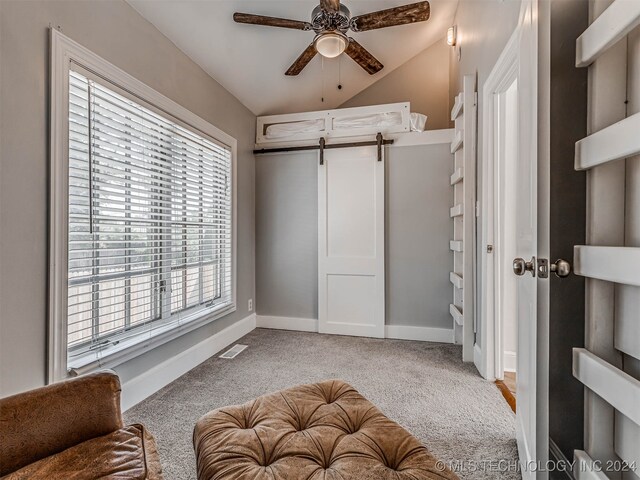 bedroom featuring a barn door, ceiling fan, vaulted ceiling, and light carpet