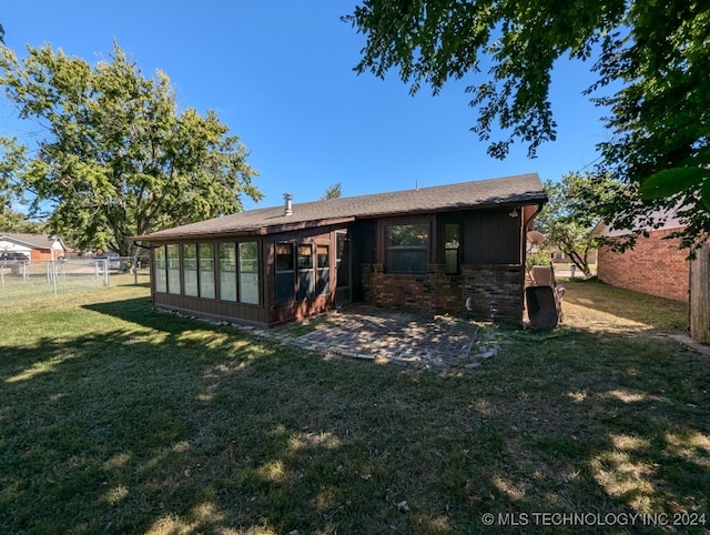 back of house featuring a lawn and a sunroom