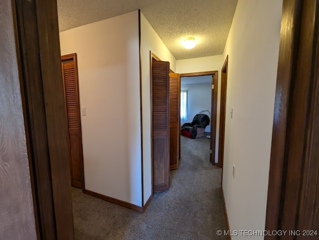 corridor featuring a textured ceiling and carpet