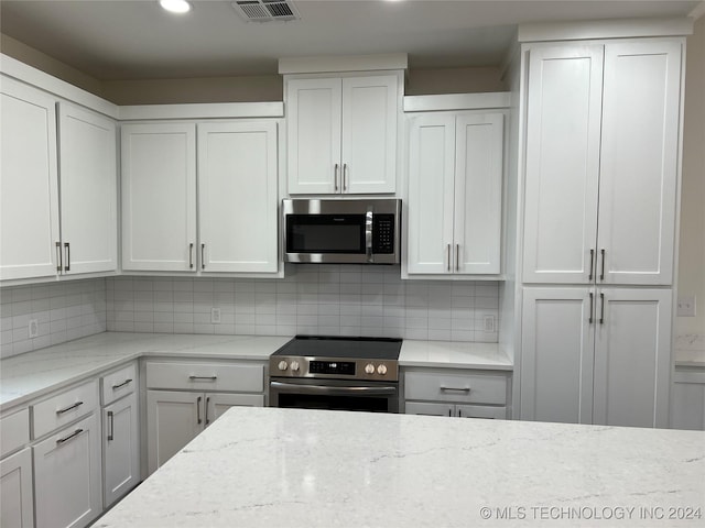 kitchen featuring decorative backsplash, white cabinetry, and stainless steel appliances