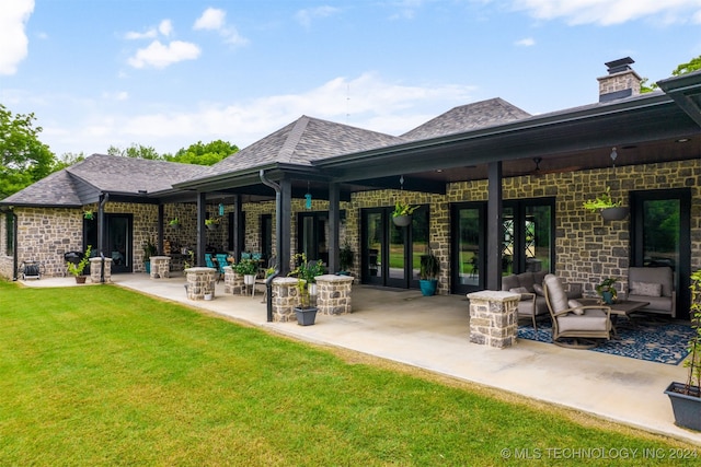 back of house featuring an outdoor hangout area, a shingled roof, a patio, stone siding, and a lawn