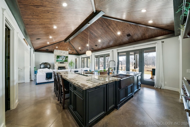 kitchen featuring baseboards, french doors, dark cabinetry, and finished concrete flooring