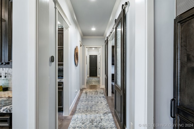 hall with baseboards, a barn door, and crown molding