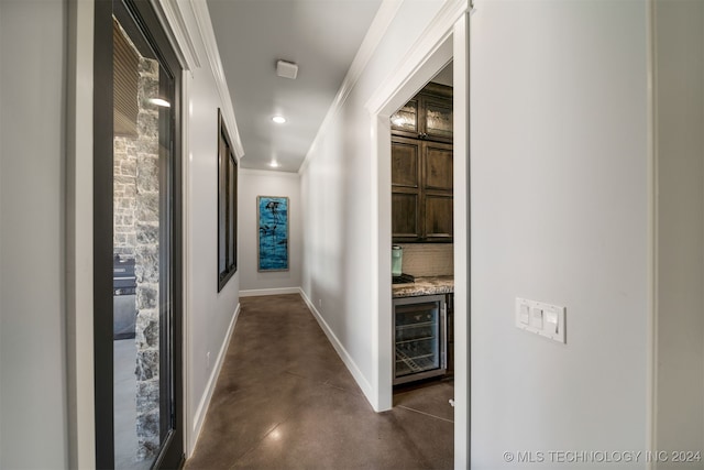 hall featuring wine cooler, baseboards, recessed lighting, finished concrete flooring, and ornamental molding