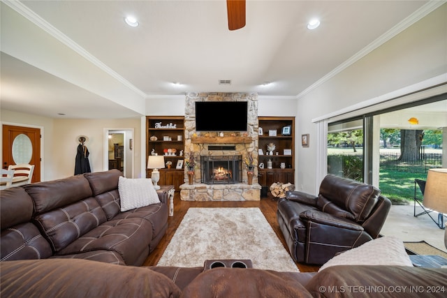 living room with wood-type flooring, a fireplace, crown molding, ceiling fan, and built in features