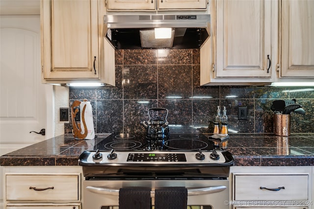 kitchen featuring light brown cabinets, gas range, tasteful backsplash, and ventilation hood