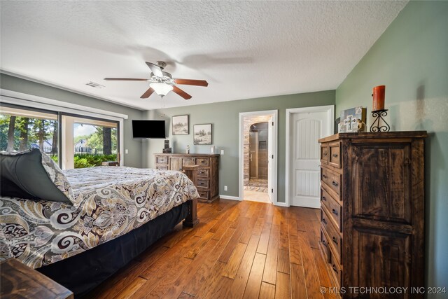 bedroom with ceiling fan, hardwood / wood-style flooring, connected bathroom, and a textured ceiling