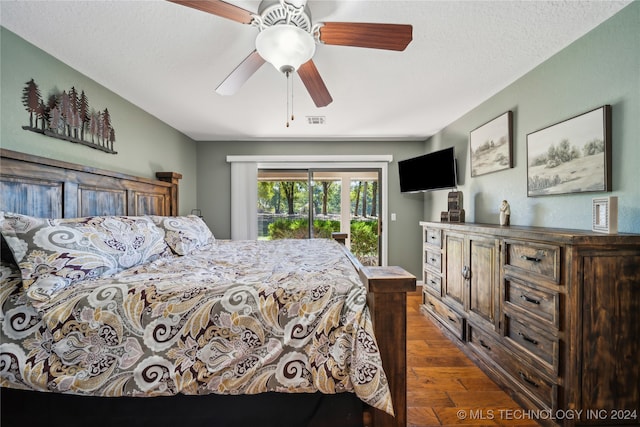 bedroom featuring ceiling fan, a textured ceiling, dark hardwood / wood-style floors, and access to outside