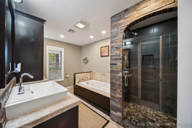 bathroom with a textured ceiling, sink, tile patterned floors, and separate shower and tub