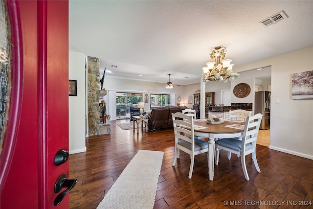 dining room featuring ceiling fan with notable chandelier, a textured ceiling, and dark wood-type flooring