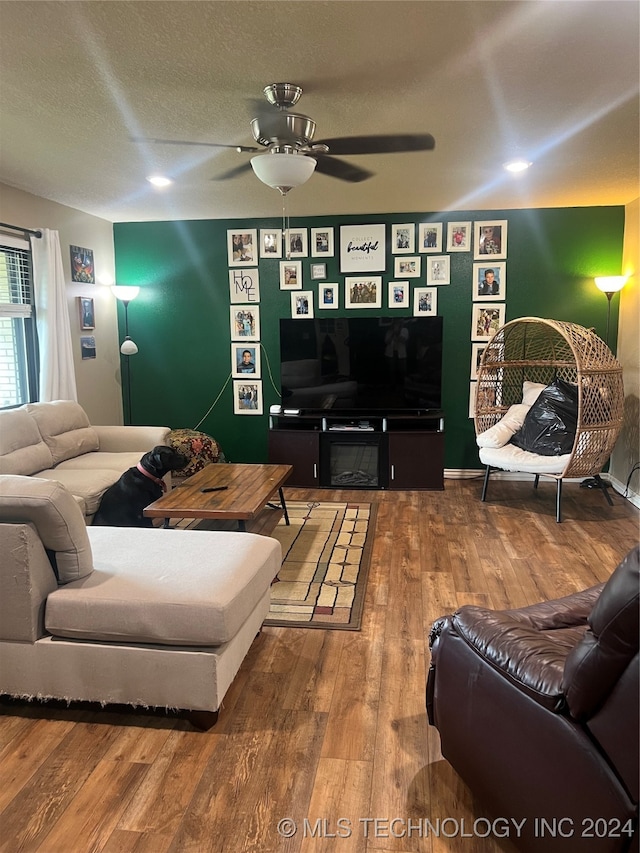 living room featuring ceiling fan, a textured ceiling, and hardwood / wood-style floors