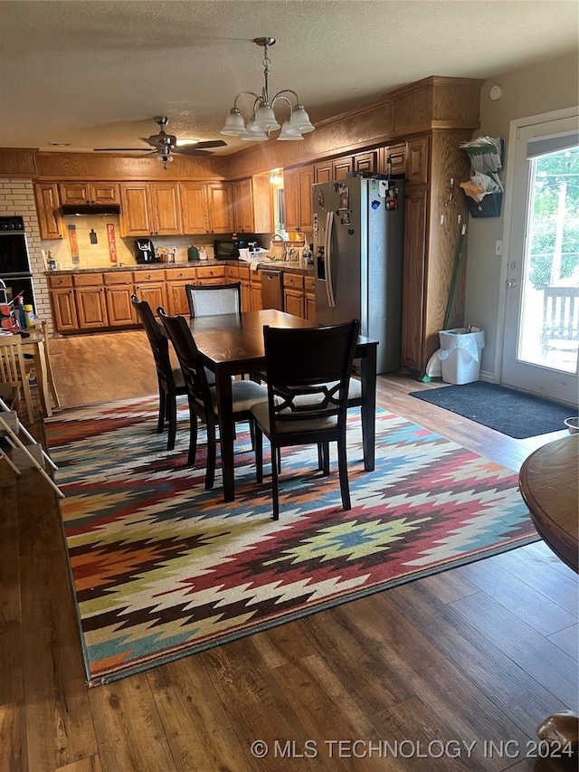 dining room featuring wood-type flooring, a textured ceiling, and ceiling fan with notable chandelier