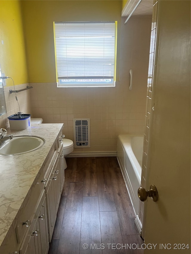 bathroom with tile walls, hardwood / wood-style flooring, vanity, and toilet