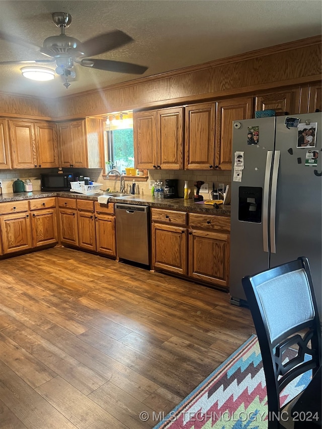 kitchen featuring sink, decorative backsplash, stainless steel appliances, hardwood / wood-style floors, and ceiling fan