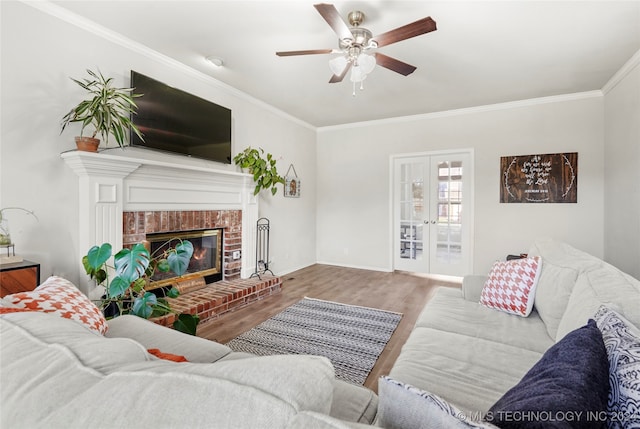 living room featuring a brick fireplace, french doors, hardwood / wood-style flooring, ornamental molding, and ceiling fan