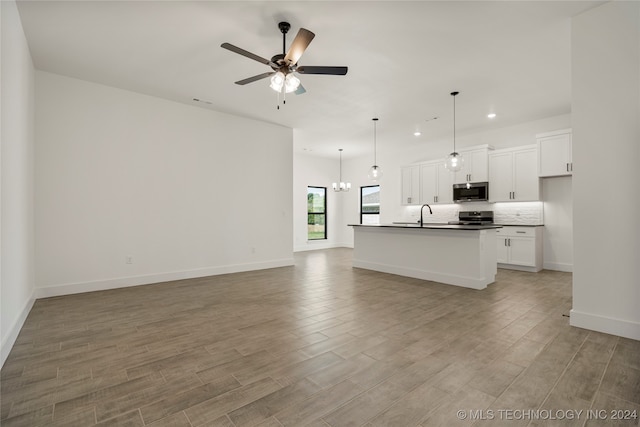 kitchen with an island with sink, light hardwood / wood-style flooring, white cabinetry, appliances with stainless steel finishes, and ceiling fan with notable chandelier