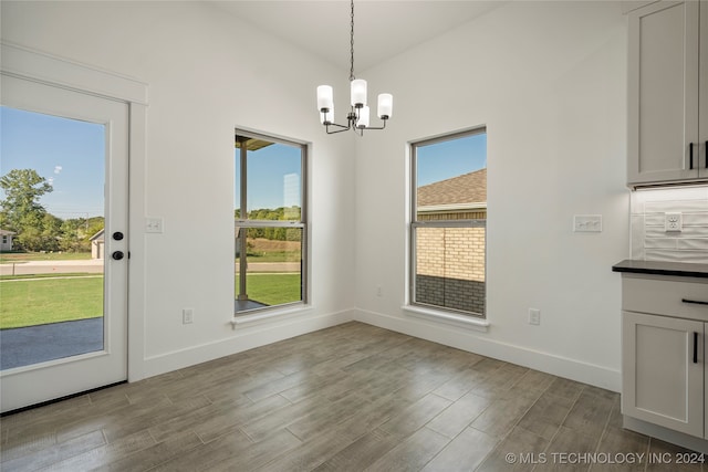 unfurnished dining area featuring a chandelier, light hardwood / wood-style floors, and a healthy amount of sunlight