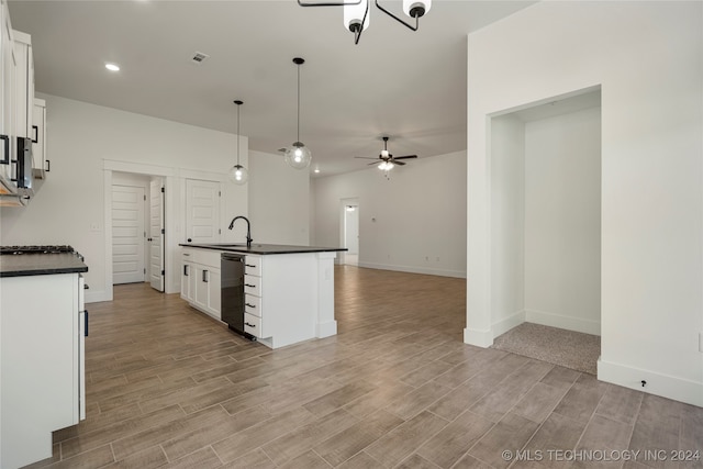 kitchen featuring ceiling fan with notable chandelier, white cabinetry, hanging light fixtures, and a kitchen island with sink