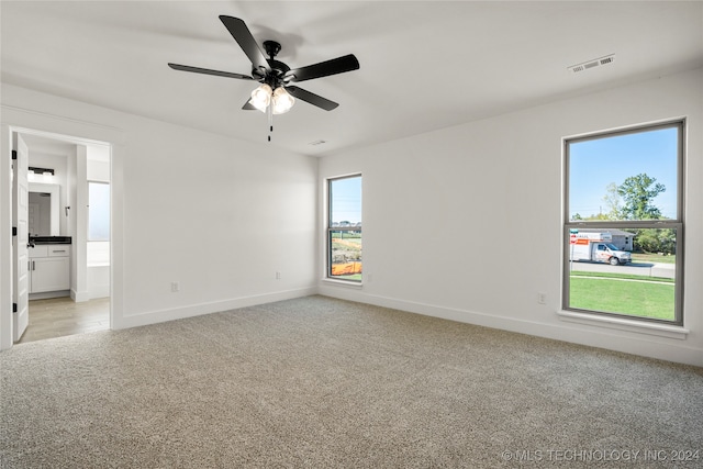 empty room with ceiling fan, light carpet, and a healthy amount of sunlight