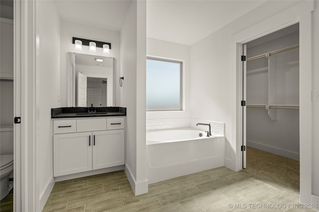 bathroom with a washtub, vanity, and toilet