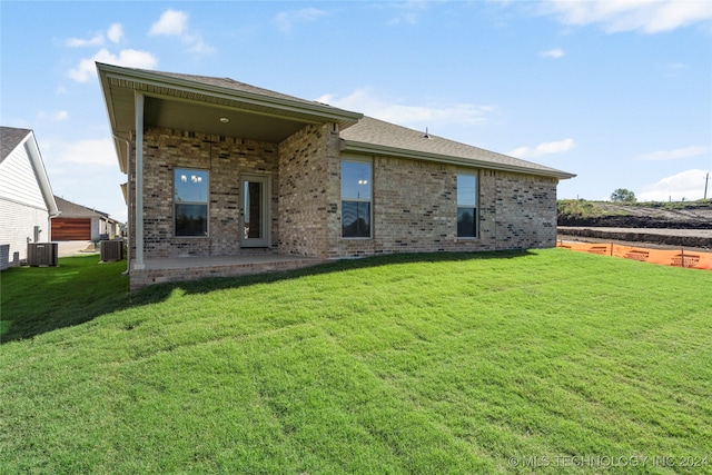 back of property with central AC unit and a yard