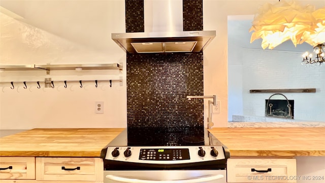 kitchen with wall chimney exhaust hood, butcher block countertops, and range with electric cooktop