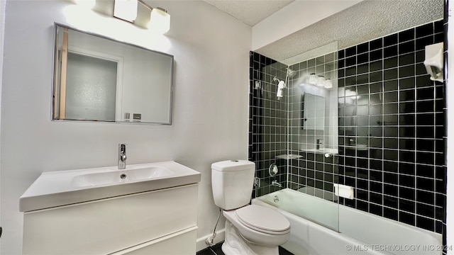 full bathroom featuring a textured ceiling, tiled shower / bath combo, vanity, and toilet