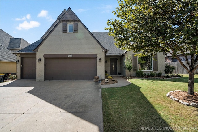 view of front of house with brick siding, fence, a garage, driveway, and a front lawn