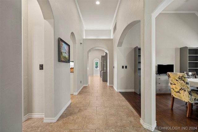 corridor with ornamental molding, arched walkways, and baseboards