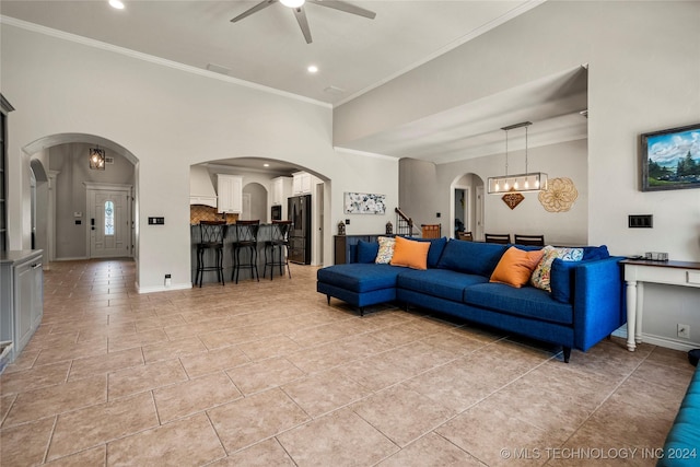 living area with arched walkways, ceiling fan with notable chandelier, and crown molding