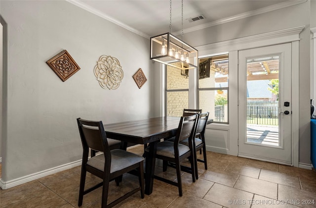 dining area with dark tile patterned flooring, crown molding, and a chandelier