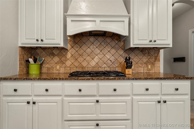 kitchen featuring white cabinetry, stainless steel gas stovetop, custom exhaust hood, and dark stone counters