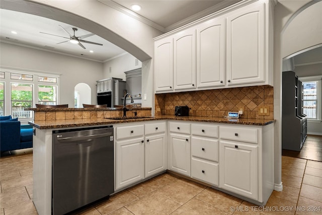 kitchen with black dishwasher, arched walkways, white cabinets, a peninsula, and a sink